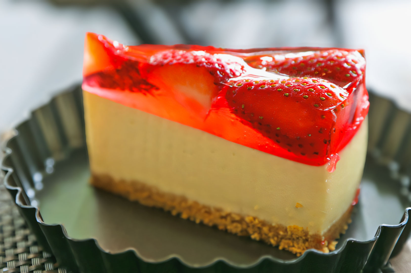 Strawberry jelly cheesecake slice with whole strawberries suspended in red gelatin on a crumb crust.