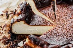 Basque burnt cheesecake with a deeply caramelized top being sliced, revealing a creamy custard-like interior on parchment paper