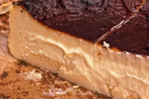 Close‑up of a sliced Basque cheesecake showing creamy interior and signature dark burnt top.