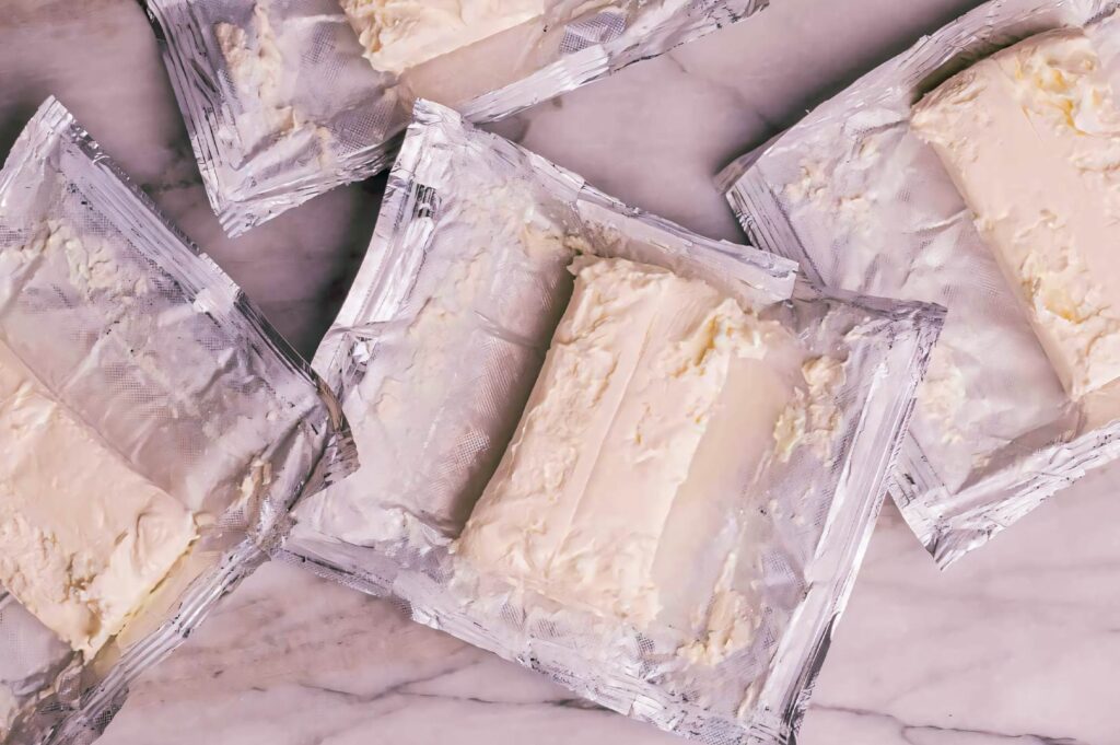 Two slices of cheesecake on a black plate, one classic New York style and one Basque burnt cheesecake.