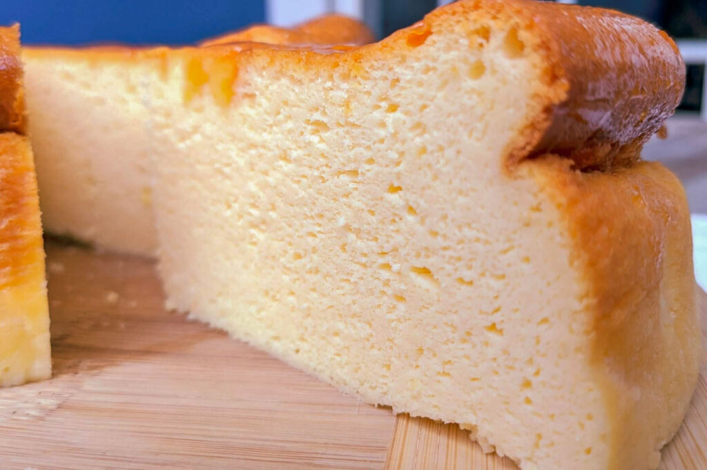 Light and airy Japanese‑style cheesecake slice showing its soft, fluffy interior texture on a wooden board.