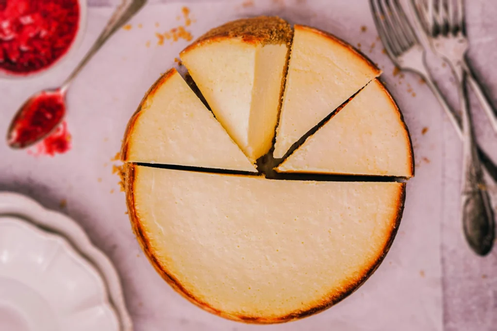 Top‑down view of a whole cheesecake cut into even slices, showing smooth baked surface and golden crust