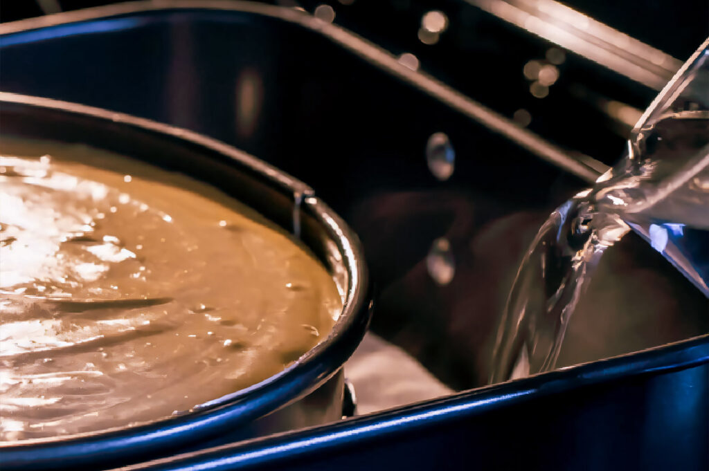 Cheesecake batter baking in a springform pan set inside a water bath for even cooking.