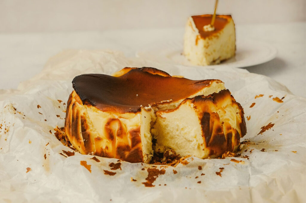 Burnt Basque cheesecake with a caramelized top and creamy interior, partially sliced and set on crinkled parchment paper