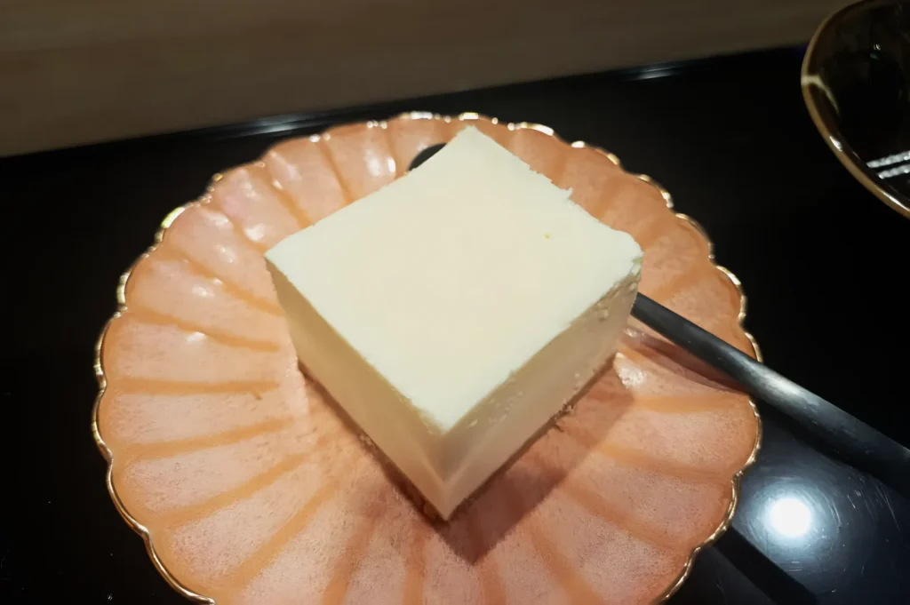 A square piece of white cake sits on an elegant pink scalloped plate with a fork beside it, reflecting a clean and inviting presentation.