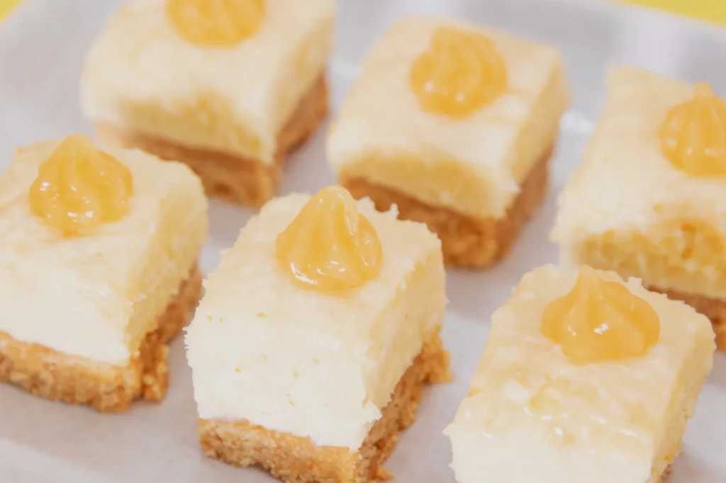 Six pieces of dessert bars with a graham cracker crust, creamy white filling, and a swirl of yellow topping.