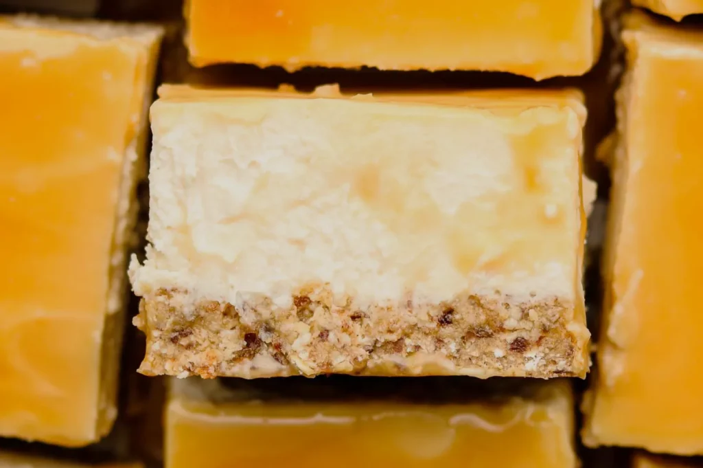 A close-up of a square piece of dessert with a creamy top and a crumbly, golden-brown base.