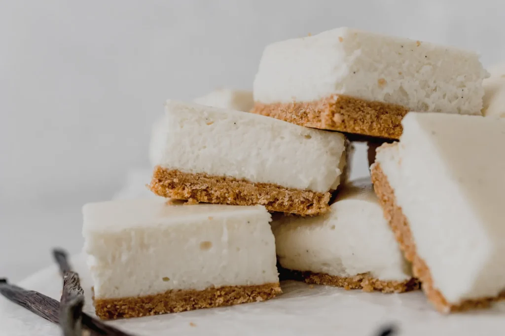 A stack of creamy cheesecake squares with a graham cracker crust.