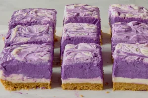 Layers of purple and white cheesecake squares on a marble surface.