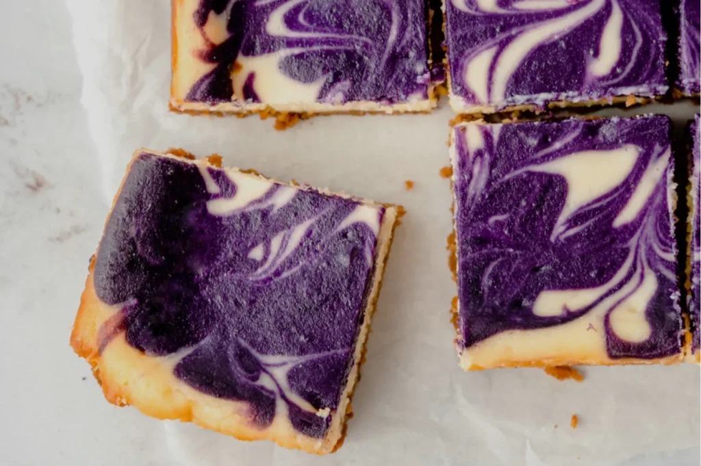A tray of purple and white marbled cheesecake squares, with one square partially removed from the tray.