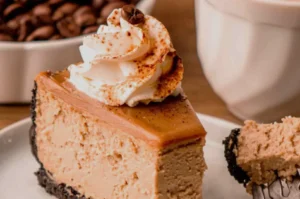A creamy coffee cheesecake slice with a dark cookie crust, topped with whipped cream and coffee beans; warm tones evoke an inviting café treat.
